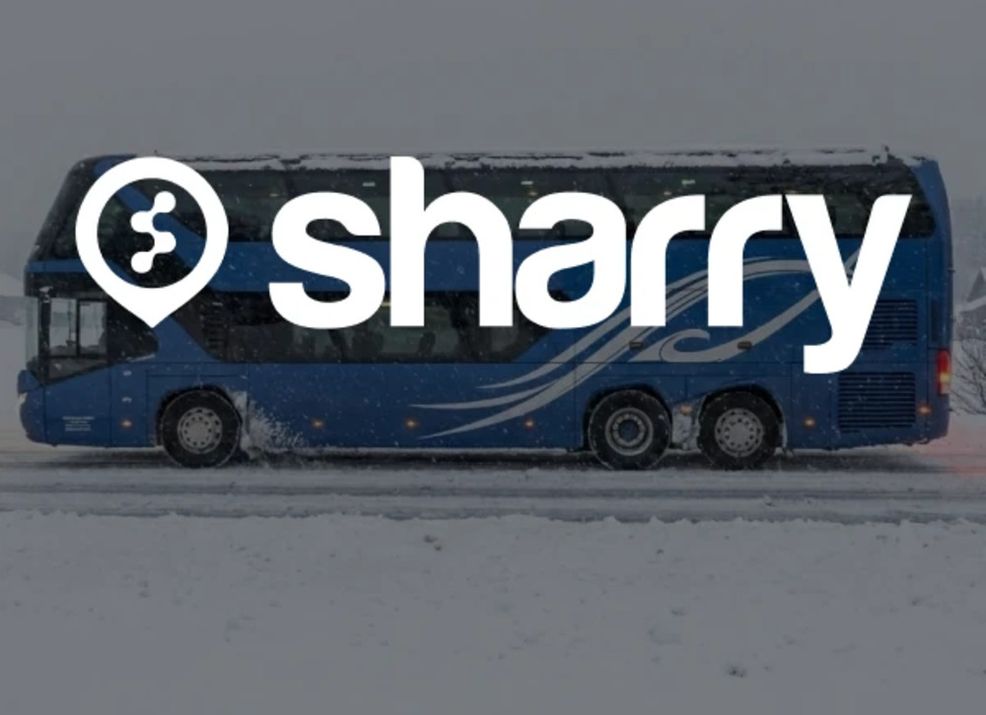 logo i nazwa firmy Sharry na tle niebieskiego autobusu, widok autobusu z boku i zaśnieżonej trasy